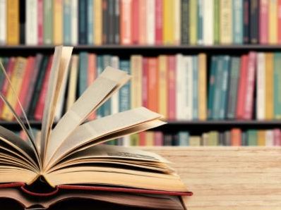 Livro aberto diante de uma estante