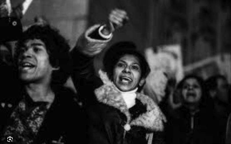 Mulheres em manifestação, com os punhos erguidos, em foto preto e branco